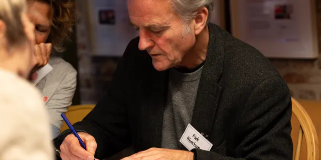 A participant writing at the table during a deep dive