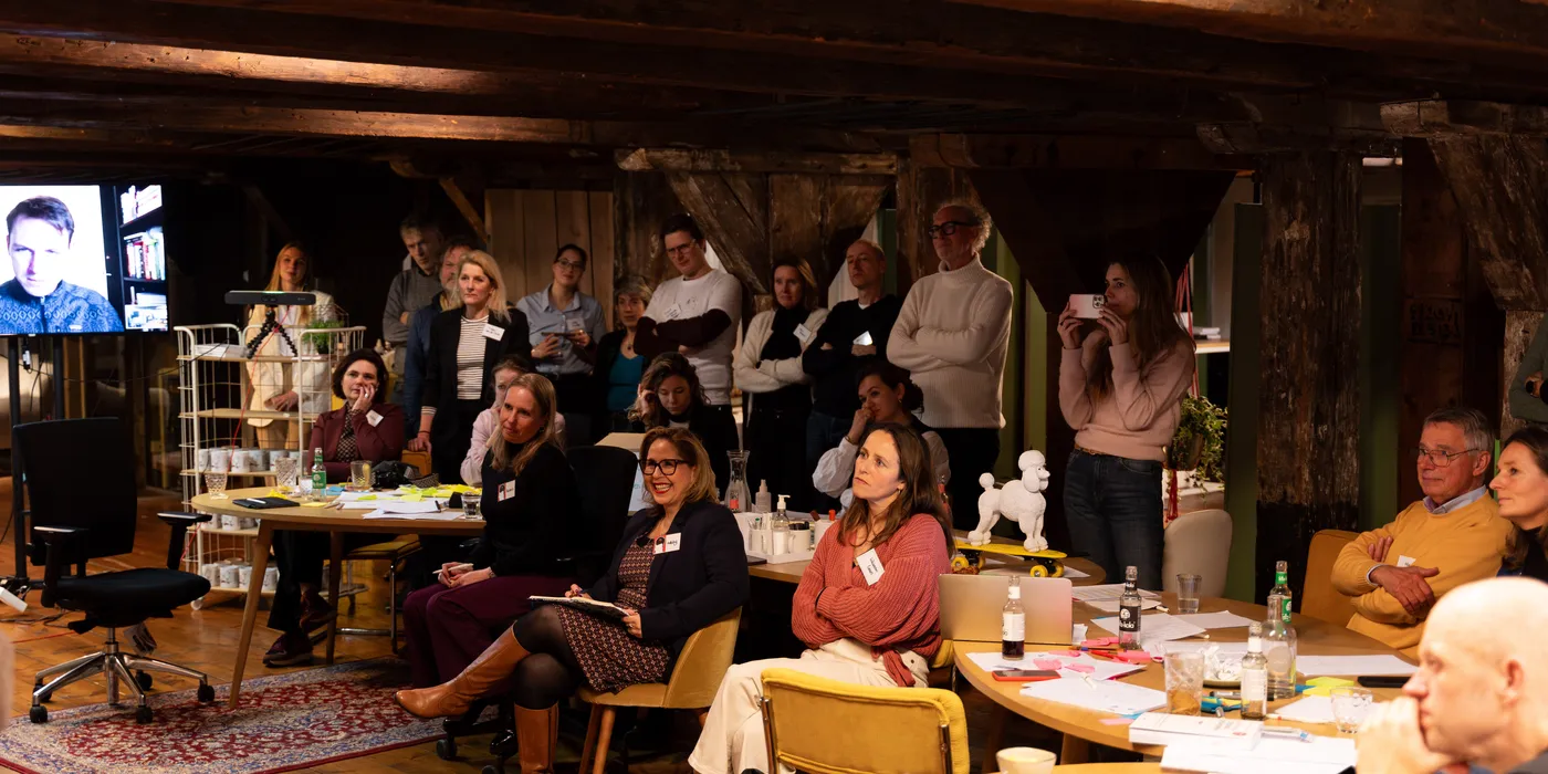 Een volle zaal lacht tijdens De Kunst van Beïnvloeden in het pand van SUE in Amsterdam